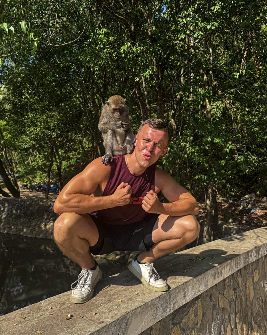 Leo with a monkey on the wall behind him in Krabi